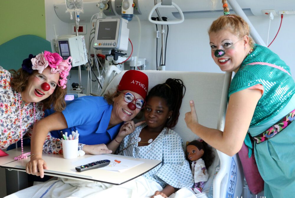 Trois clowns et une enfant avec Poupée dans un lit d'hopital