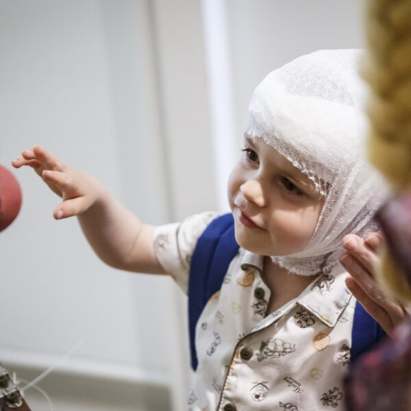 Enfant avec bandage à la tête essaynt d'attraper le nez rouge d'un clown